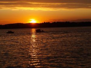 a sunset on the water with two boats at Bungalow Seedorf 4 in Basedow +2 photos