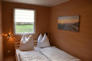 a bedroom with a bed with white pillows and a window at Bungalow Seedorf 6 in Basedow