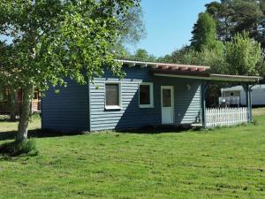 a small blue house with a white fence at Bungalow Seedorf 7 in Basedow +2 photos