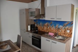 a kitchen with white cabinets and a sink and a table at Ferienwohnung Seedorf in Basedow