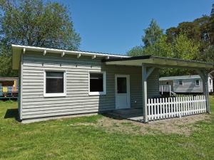 a small house with a white fence in a yard at Bungalow Seedorf 8 in Basedow +6 photos