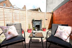 a patio with two chairs and a table with a fireplace at Radnor Rest in Folkestone