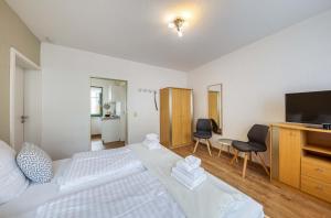 a bedroom with a white bed and a television at Am Müritzer Hafen App 1 in Waren