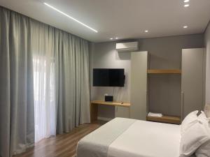 a hotel room with a bed and a television at Arvi Boutique Hotel in Lukovë