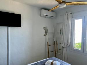 ein Schlafzimmer mit Fernseher und Bett mit Handtüchern in der Unterkunft Miravent Terraza y Jardin Frente al mar Menorca in Fornells