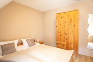 a bedroom with two beds and a wooden cabinet at Am Müritzer Hafen App 4 in Waren