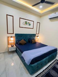 a bedroom with a large bed with a blue headboard at Norway Residency in Jagādhri