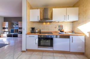 a kitchen with white cabinets and a stove top oven at Ferienwohnung Sonnendeck in Klink