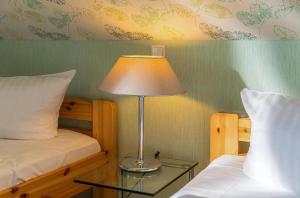 a lamp on a glass table next to two beds at Ferienwohnung Sonnendeck in Klink +3 photos
