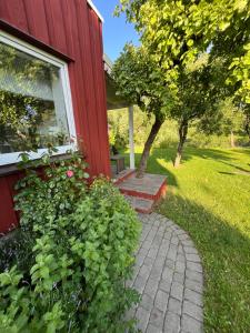 a red house with a brick walkway next to a window at River Side Studio, 9mi from Palanga, With sauna in Kretinga