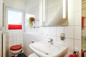 a bathroom with a sink and a toilet and a window at Ferienwohnung Argenpark Kressbronn in Kressbronn am Bodensee