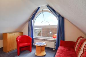 a living room with a red chair and a window at Ferienwohnung Argenpark Kressbronn in Kressbronn am Bodensee