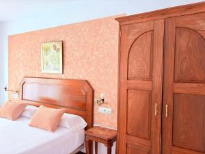 a bedroom with a bed and a wooden cabinet at Hotel Alandalus in Torrox +8 photos