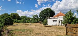 a white house in a field with trees at Dãnu Guesthouse in Kravany nad Dunajom