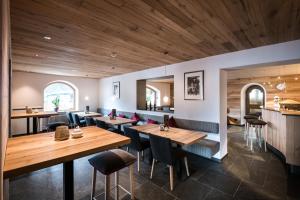 a restaurant with wooden ceilings and tables and chairs at Hotel Ciasa Tamá in La Villa