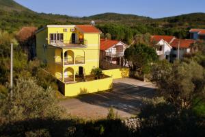 a yellow house in the middle of a village at Apartments Villa-G Lustica in Tivat