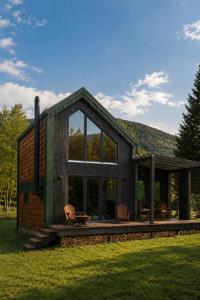 a wooden house with a large window and chairs at Tysha in Tatariv