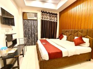 a bedroom with a bed and a desk and a television at Hotel Gareen By Du Rooms Near Delhi University Kamlangar in New Delhi