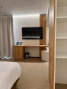 ein Hotelzimmer mit Schreibtisch und Fernseher in der Unterkunft Hotel Sirius in Huy