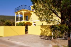 a yellow house with a fence in front of it at Apartments Villa-G Lustica in Tivat