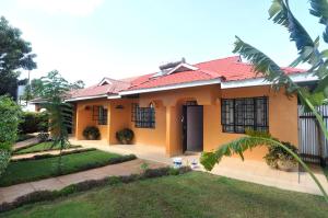 a yellow house with a red roof at Majimbo Whitehouse Resort in Ramogi