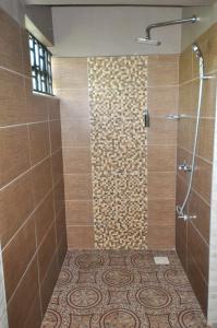 a bathroom with a shower with a tile floor at Majimbo Whitehouse Resort in Ramogi