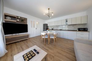 a living room with a table and a kitchen with white cabinets at Mountain View House Brasov in Braşov