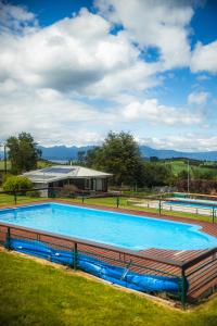 a large swimming pool in a field with a house at Centro Turistico Lafquintue in Ranco