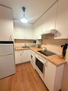 a kitchen with white cabinets and a stove top oven at El Boj in Canfranc +10 photos