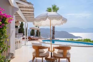 a villa with a pool and a patio with chairs and an umbrella at Villa Achilleas Crete in Ierapetra