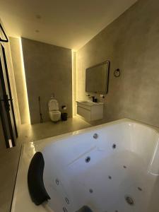 a bathroom with a tub and a tv on the wall at Trio Luxury Apartment 3 in Sowayma +5 photos