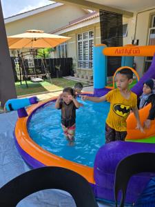 two children are playing in an inflatable pool at Homestay DAR AL - JUFRY fully aircond in Kuantan