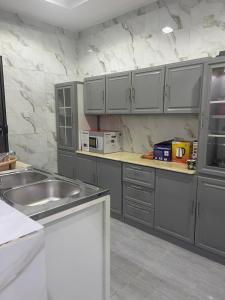 a kitchen with gray cabinets and a stainless steel sink at شقق مفروشة الطارق in Ḩaql