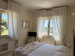 a bedroom with a bed and two windows at Hotel Bagni Lido in Vada