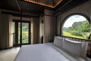 a bedroom with a large bed with a large window at An Hideaway Resort in Ninh Binh +81 photos