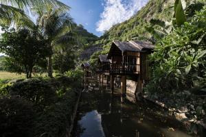 a house on a river next to a mountain at An Hideaway Resort in Ninh Binh