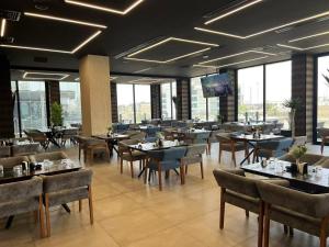 a dining room with tables and chairs and windows at Taj Premium Hotel in Baghdād
