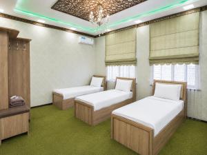 two beds in a room with green carpet at Zamin Hotel in Shahrisabz