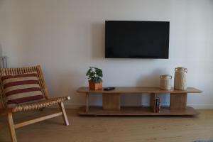 a living room with a table and a chair and a television at Alfaiate Beach House in Santa Cruz