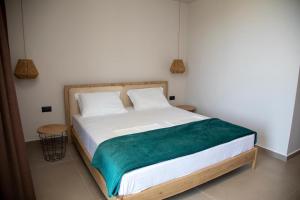 a bedroom with a bed with a green blanket on it at Uzeiri Guest Hotel in Borsh