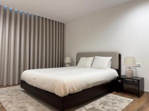 a bedroom with a bed with white sheets and curtains at Apartamento do Teatro in Lamego