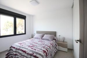 a bedroom with a bed with a striped blanket and a window at La Morada de Sasa Casa tierra in Torrent