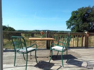 two chairs and a table on a wooden deck at La Grange des Lavandes in Mérinchal