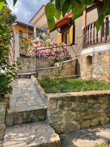 a house with a stone retaining wall and pink flowers at Capris Rustic Ηouse with Mountain View in Archaia Feneos