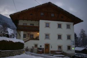 a large white house with a wooden roof in the snow at Thalerhof in Roppen