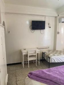 a bedroom with a desk and a tv on the wall at Hôtel Dar Massmoudi in Tunis