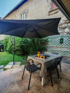 a table and chairs under an umbrella on a patio at Le Pène de Béon in Aste-Béon