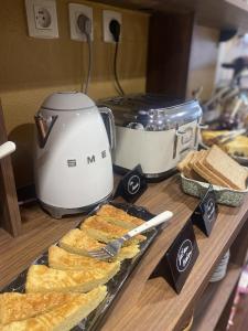 a counter with bread and a toaster and a table with food at Louis Hotel in Perros-Guirec