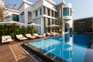 a swimming pool in front of a house with umbrellas at Shintana Saya Residence in Siem Reap