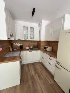 a kitchen with white cabinets and a white refrigerator at Dolce Vita in Gdynia
